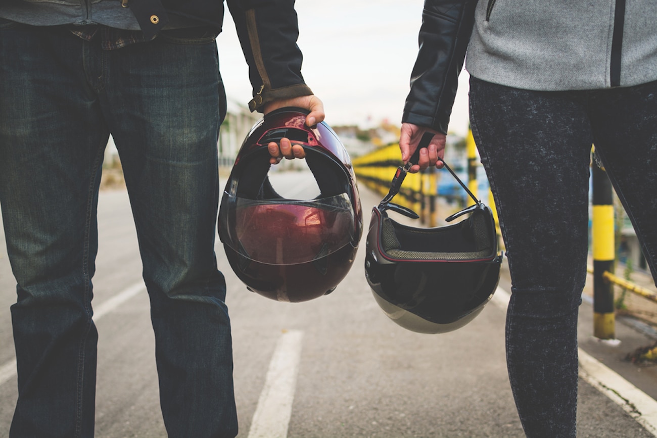 motorcyclists holding helmets