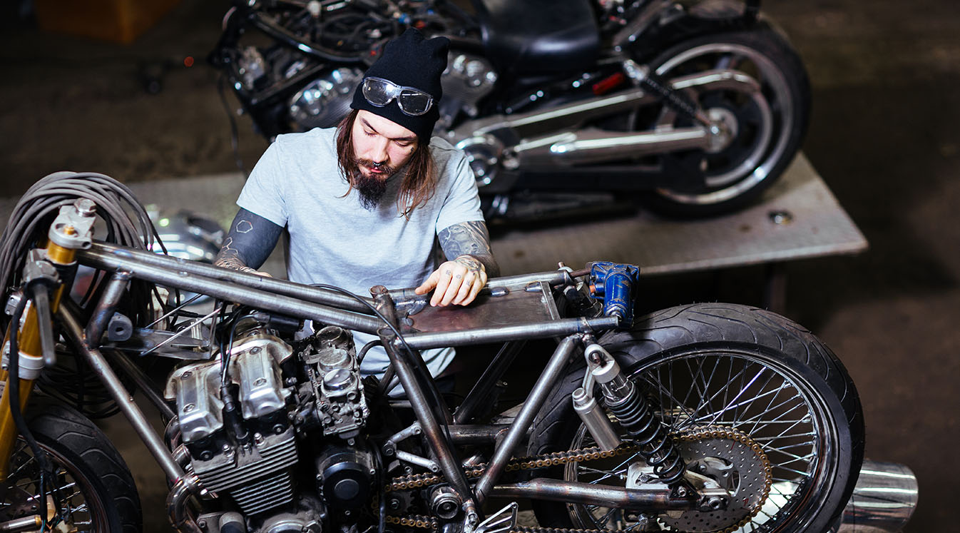 Portrait of tattooed man working in garage customizing motorcycle