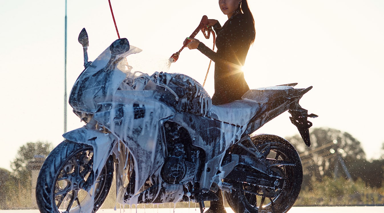 woman washes a motorcycle at self service car wash