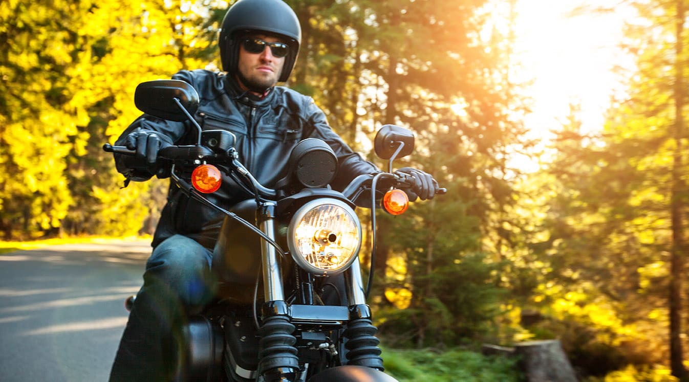 Motorcyclist riding a chopper on a road in morning sun